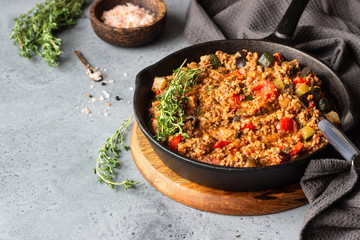 Pan of italian sauce bolognese with thyme on grey concrete background. Copy space.