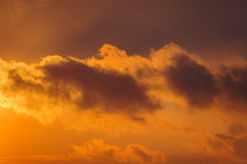 Dramatic view of a dark silhouettes of clouds in the orange sky illuminated by the rising sun