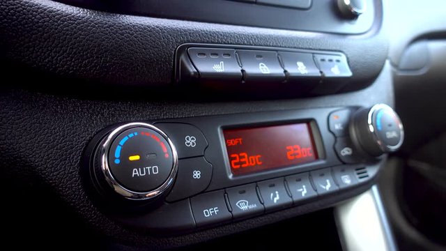 Man press the climate control button and adjusts the temperature in the car. 4K