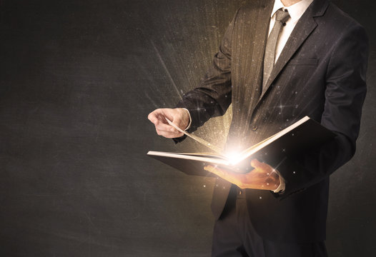 Man holding and reading a shiny book.