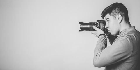 Profile portrait of young photographer with camera. Monochrome image with copy space. © kavzov