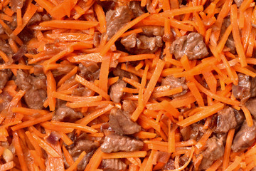Roasting vegetables and meat in a frying pan with non-stick coating. Onion, carrots and meat. Close-up