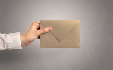 Fototapeta premium Female hand holding coloured and white envelope with empty wall background 