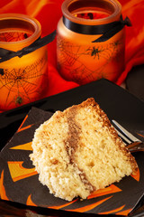 Coffee crumble cake decorate Halloween concept. Black plate and orange candle. Selective focus.