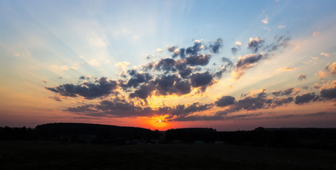 Obraz premium sunset dawn sun rays over the city sky field of flowers