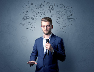 Businessman speaking into microphone with mixed doodles over his head