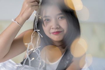 Close up portrait of young woman playing with mini Christmas lights