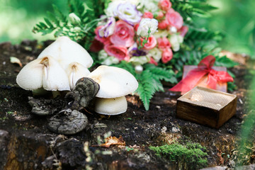 Obraz na płótnie Canvas Wedding rings, bouquet and mushrooms on hemp