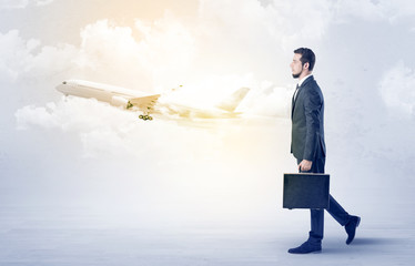 Elegant businessman going somewhere with briefcase and airplane on the background
