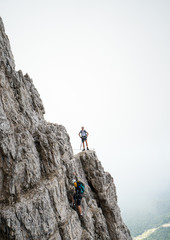 two young attractive male mountain climbers on very exposed Via Ferrata in the Dolomites of Italy