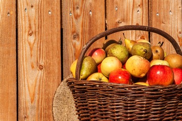 Wicker basket with apples and pears. Autumn harvest of fruit. Fresh fruit in a basket.
