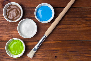 Brush and colorful paint in jars on an old wooden background with copy space