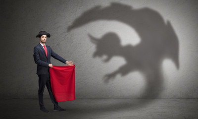 Businessman standing with red cloth in his hand and imp shadow on the background
