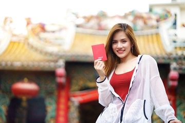 Young traveler asian woman travels to Thailand, holding red passport in hand and carry bag, visit China Temple at China Town during holiday or vacation. Feeling happiness , smiling and cheerful