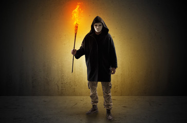 Ugly scary man with burning flambeau walking in an empty space