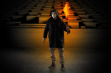 Ugly, aberrant man coming out from the labyrinth with burning flambeau on his hand
