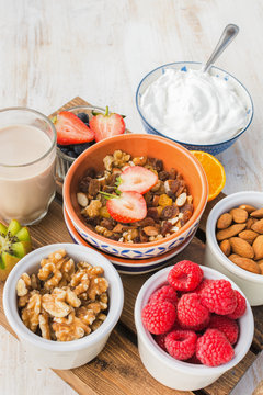 Oat free paleo nut and fruit granola served with fruits and berries, nut milk, coconut yogurt, vertical, selective focus