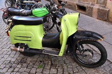 Grüner Motorroller und grünes Moped auf grauem Kopfsteinpflaster