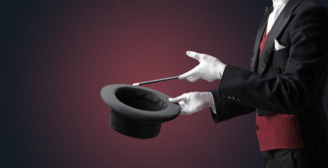 Illusionist white hand wants to conjure with magic wand from a black cylinder something