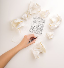 Female hand next to a few crumpled paper balls drawing charts and graphs