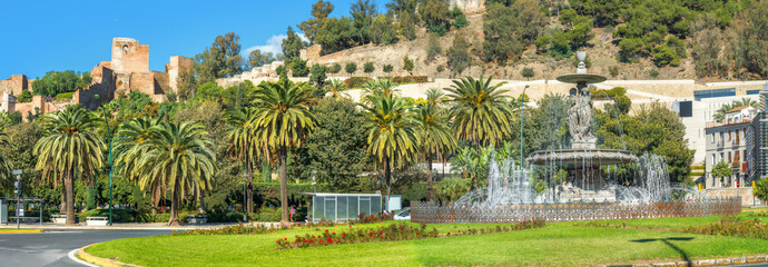 Fototapeta na wymiar Beautiful fountain and panoramic view of Alcazaba fortress wall in Malaga. Andalusia, Spain