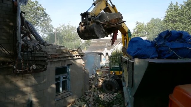 Demolition house using excavator in city. Rebuilding process.