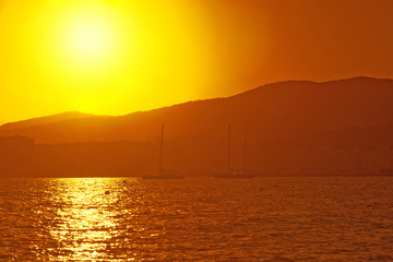 Sailing yachts in golden haze at sunset