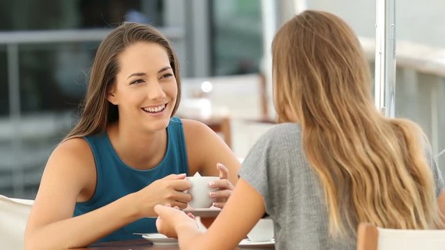 Two happy friends talking laughing and relaxing in a coffee shop