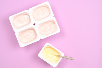 Plastic cup with tasty yogurt on lilac background. Top view. Space for text or design.