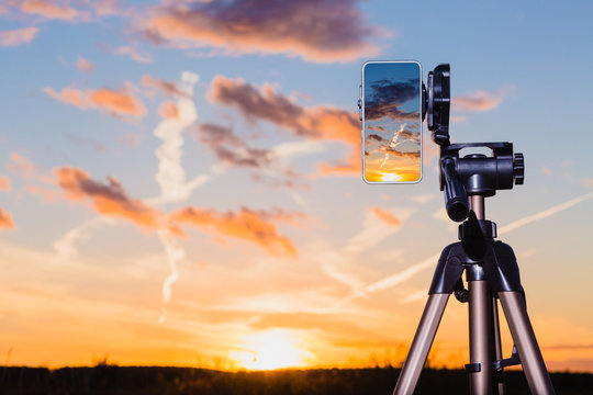 Smartphone on tripod capturing image of sundown in vertical mode