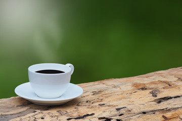 Coffee cup on brown wood in the morning and green background. Copy space