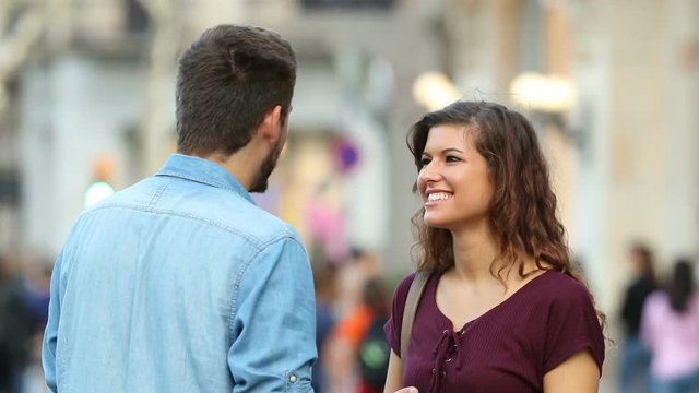 Happy woman talking with a man in the street