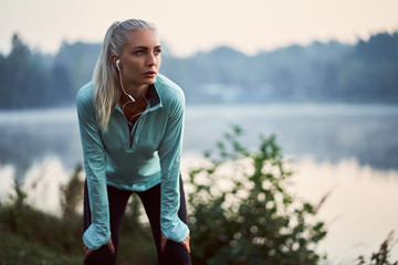 Female jogger listen to music while having rest during early morning exercise