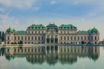 Fototapeta na wymiar Full view of a baroque Upper Palace in historical complex Belvedere, Vienna, Austria with cloudy sky. It is a popular touristic attraction with famous museum and beautiful park with pond