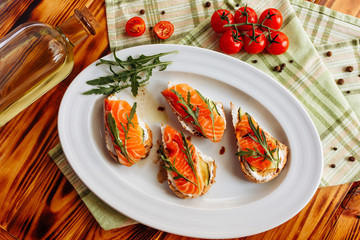 Whole grain bread with avocado paste and salmon decorated with arugula. Top view
