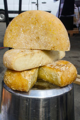 Yellow cheese half wheels are placed on the top of metal bucket asadvertisment