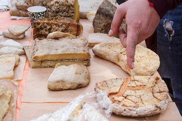 Finger is pointing at the chosen piece of homemade brown cheese