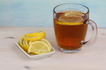 Glass of tea with lemon. Bowl with sliced lemon.