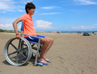 Young boy with wheelchair on the beach and shorts
