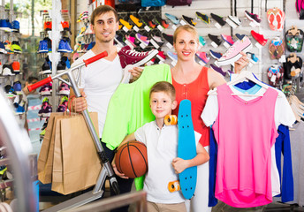 Obraz na płótnie Canvas Couple with boy choosing shoes in sport shop