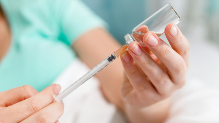Closeup photo of woman filling syringe with medicines