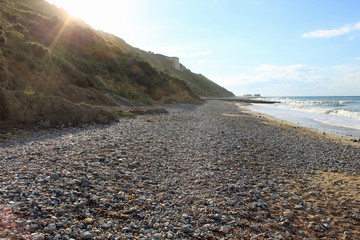 Fototapeta na wymiar A gravel beach with a hill on the left side