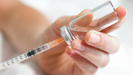 Macro image of nurse filling small syringe with drugs from vial