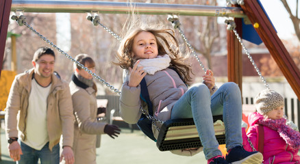 Fototapeta premium family with two girls having fun on swings outdoors