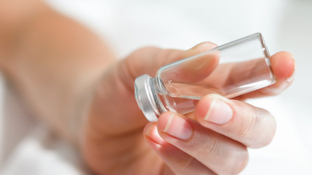 Closeup image of nurse holding glass ampule with medication