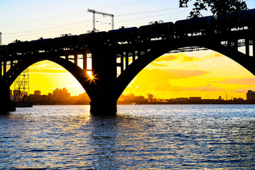 Naklejka premium Silhouette of a beautiful arched railway bridge and wagons on the Dnieper river at sunset. Dnipropetrovsk (Dnepr, Dnipro, Dnepropetrovsk) Ukraine.