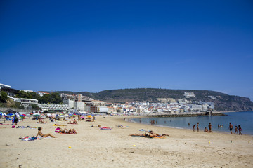 People on the beach with village on the background
