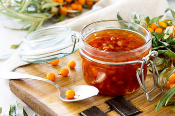 Homemade jam. Glass jar with sea buckthorn jam on rustic background. Preserved berry. Copy space.