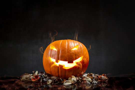 Composition of pumpkin on black background with glowing smoke. Horizontal orientation