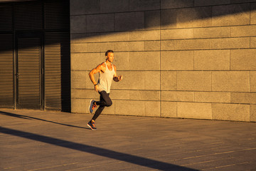 Active gogger man running at daytime in the urban city at morning and sunlight is shining at him. oudoor sport, running and workout for healthcare